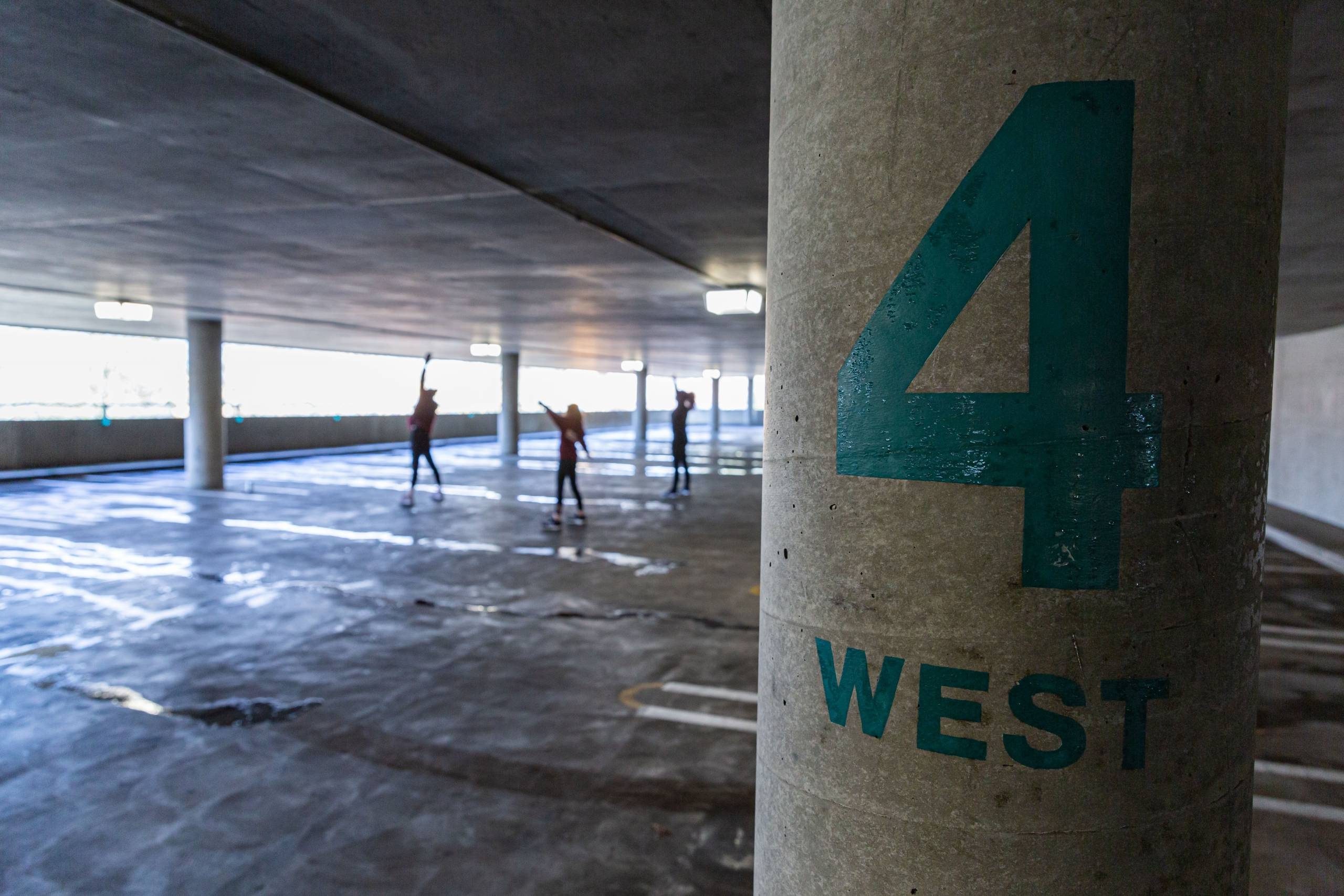 Image of dancers performing in a parking garage with a column that says 
