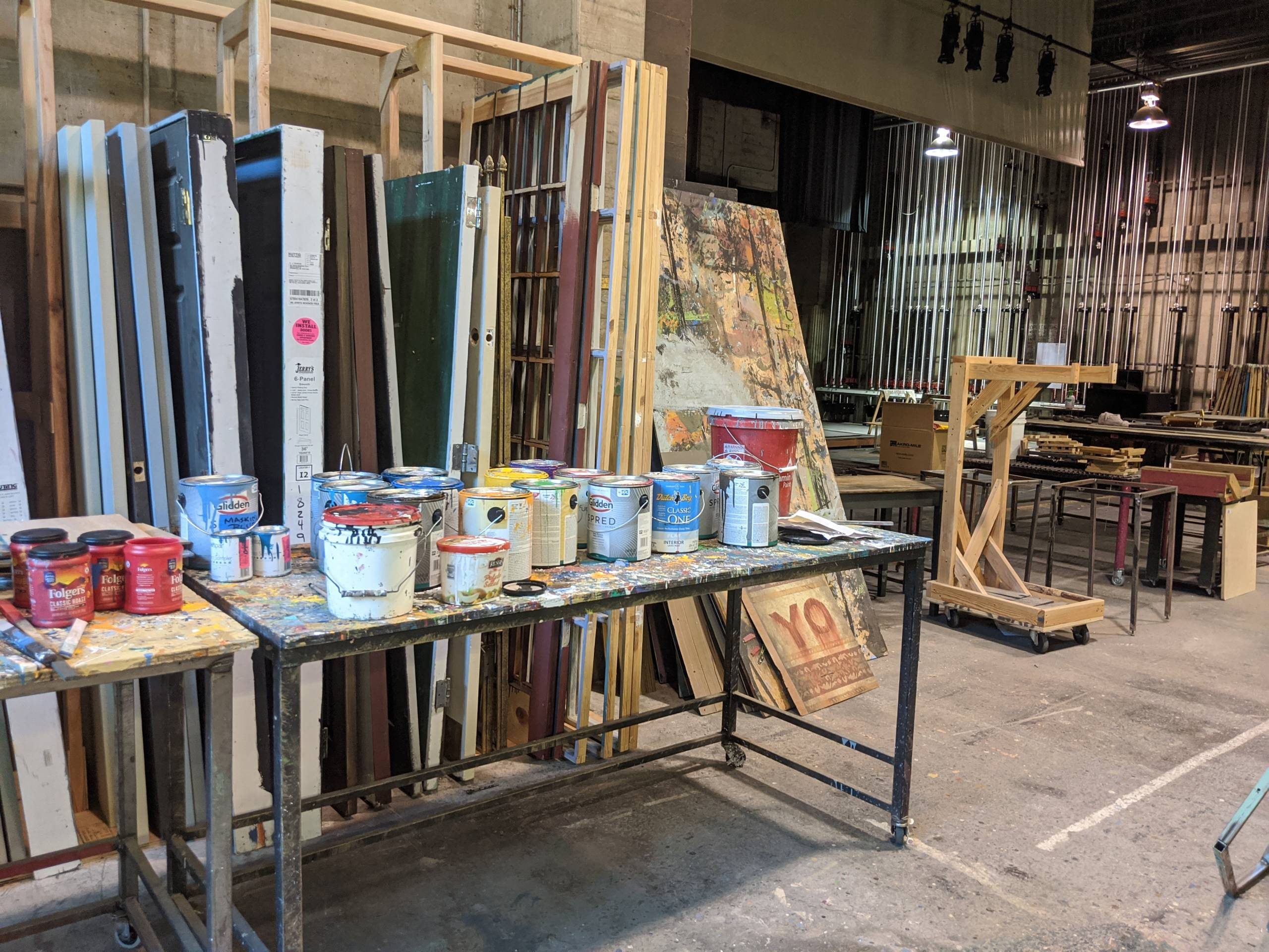 A room filled with paint buckets, ply wood boards and power tools