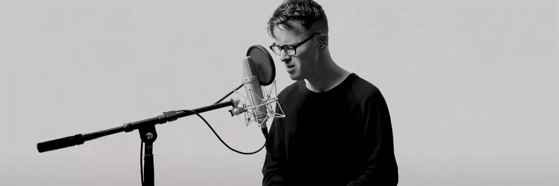 Black and white image of Ryan Lott playing the keyboard and singing into a microphone