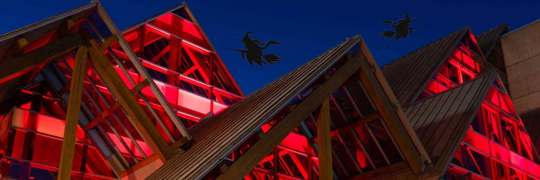 A picture of the Hult Center's exterior lit up in red with black silhouettes of witches above the building