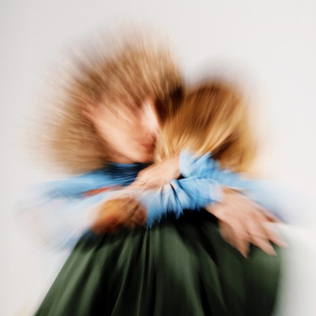 A blurred image of two individuals in an embrace.